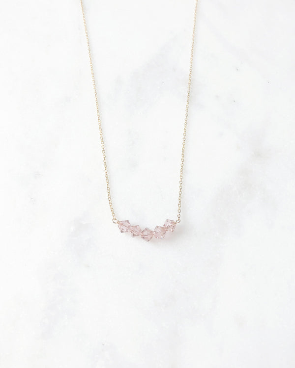 Flatlay of the Stardust Bridesmaid Necklace in gold with blush crystals.