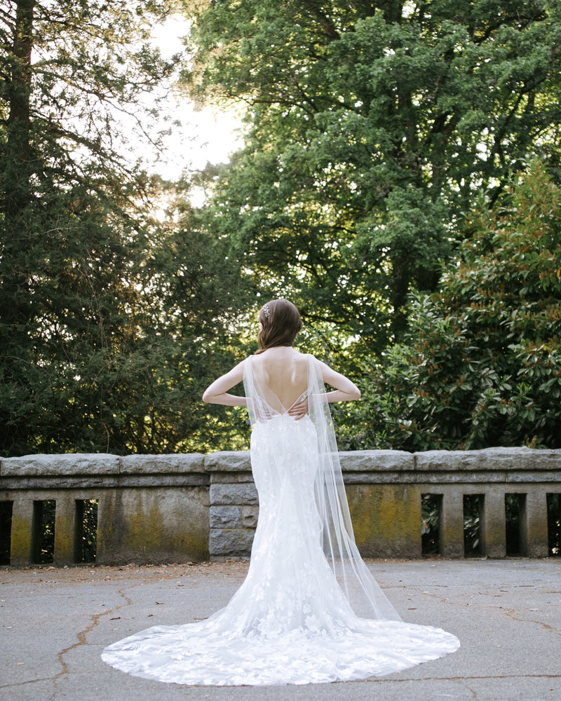 A back view of a bride wearing the Aster Cape Veil in chapel length.