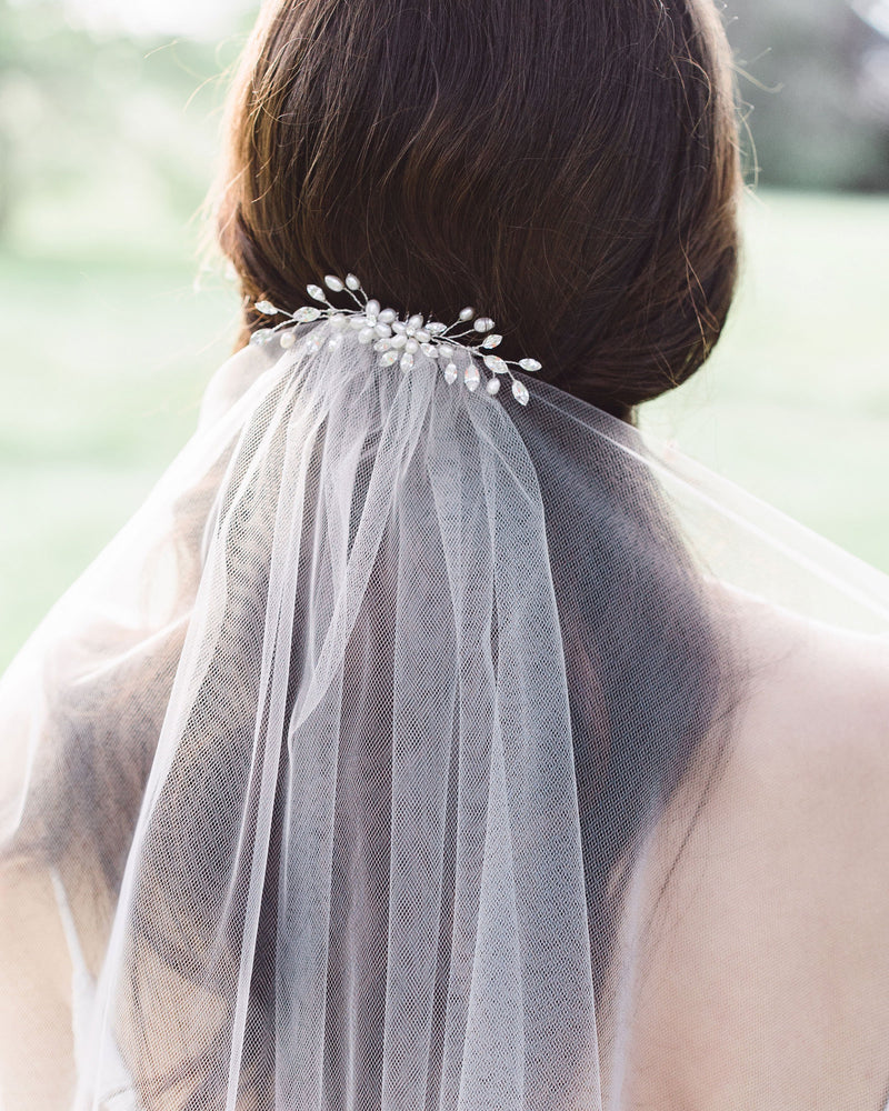 A bride wears a wedding hair comb with pearls and crystals over her bridal veil.
