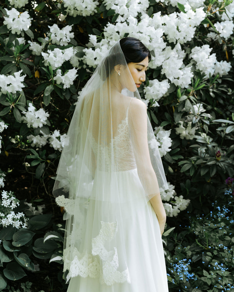 A bride wears the Azalea two-layer veil with lace border on bottom layer and soft blusher worn to the back.