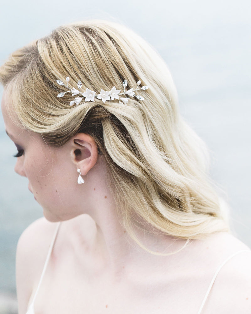 Close-up of a bride with blonde hair and soft waves wearing a bridal hair comb with crystals, flowers, and pearls.