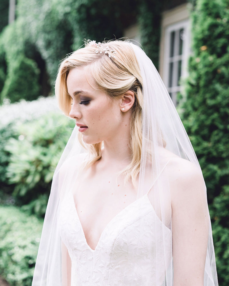 A bride wears the Belle Fleur Grand Crown in her blonde hair, which is styled with loose waves. The headpiece is paired with a simple veil.