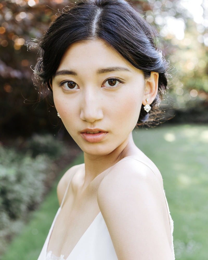 A model with a bridal updo is wearing the Celestial Crystal Drop Earrings in gold, all crystal.