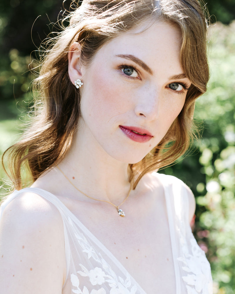 A bride with auburn hair models the Celestial Crystal Drop Necklace in gold/crystal and matching Celestial Crystal Stud Earrings.