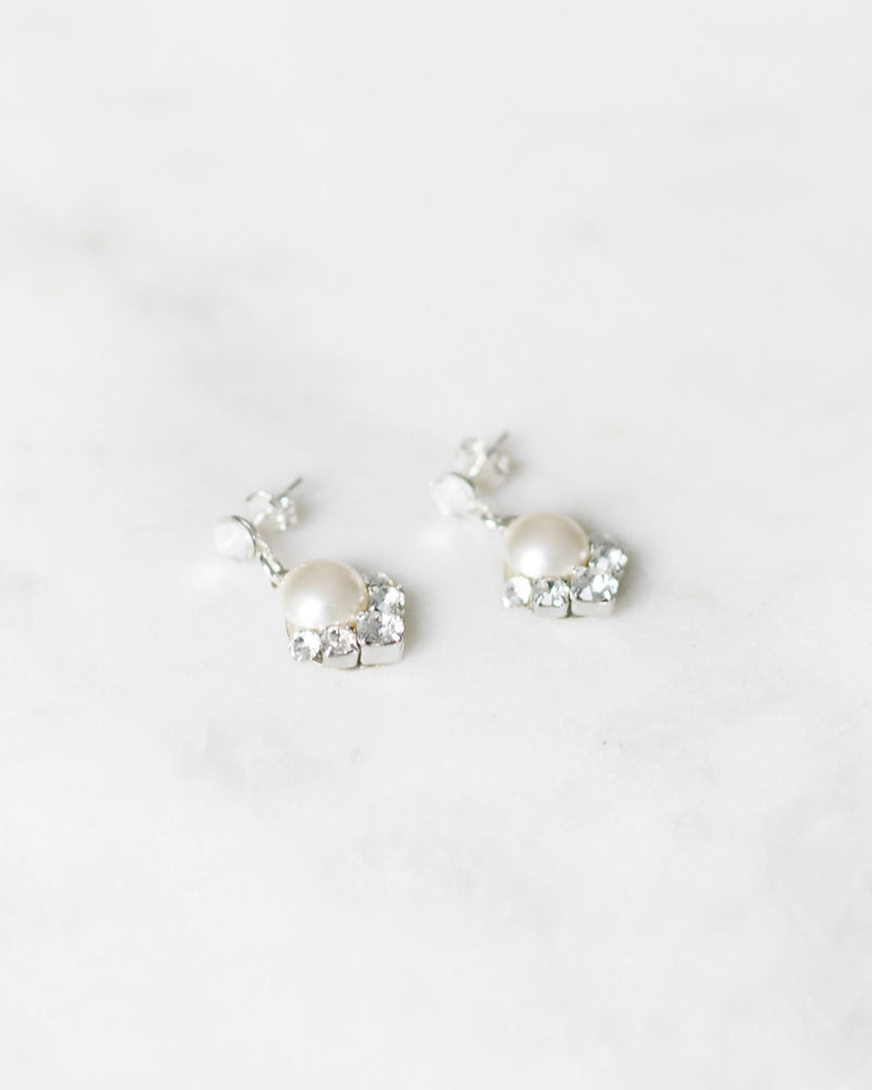 A flatlay view of the Celestial Pearl Drop Earrings in silver with cream pearls.