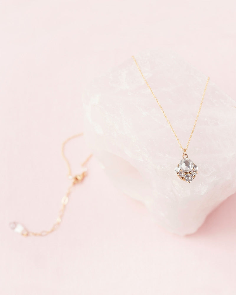 Product view of the Celestial Crystal Drop Necklace in gold, styled on a piece of rose quartz.