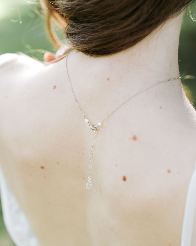 A back view of a model wearing our Celestial Pearl Drop Necklace, showing the dainty crystal drop at the back.