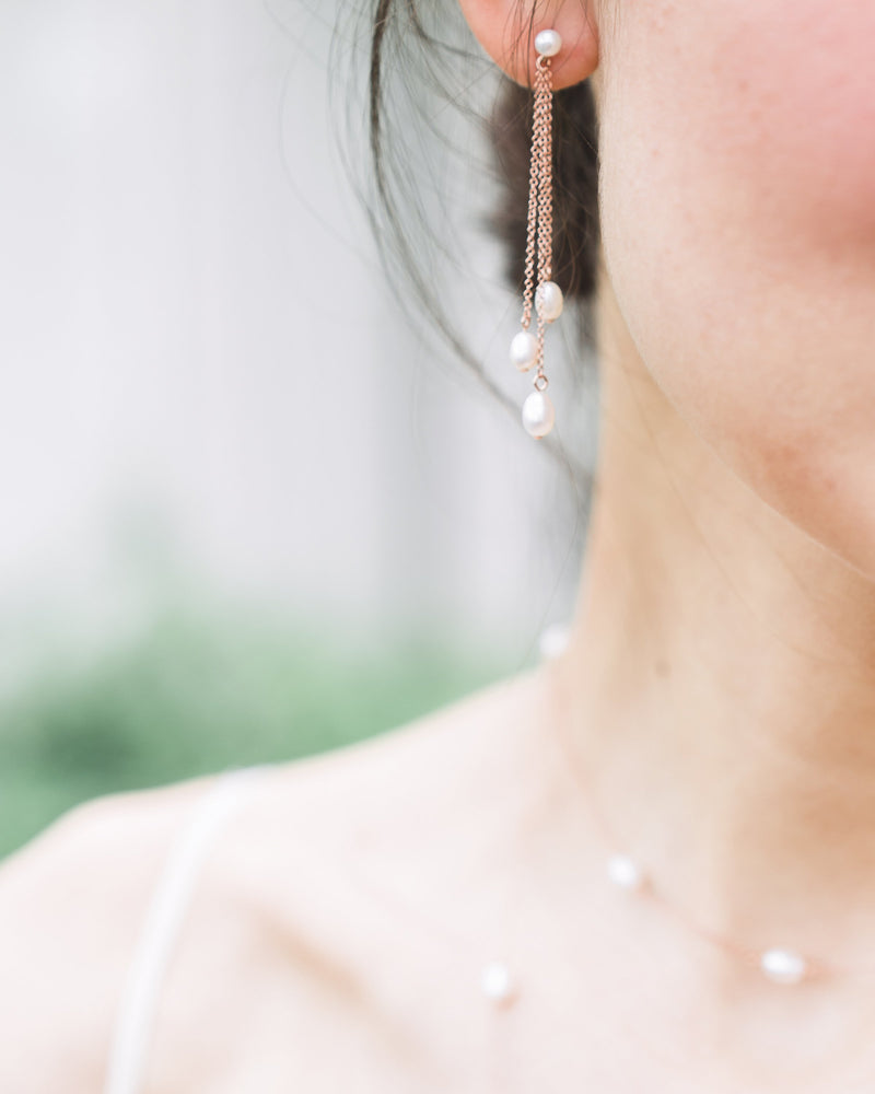Close-up on model of the Dainty Pearl Trio Earrings, paired with the Dainty Pearl Layered Necklace.