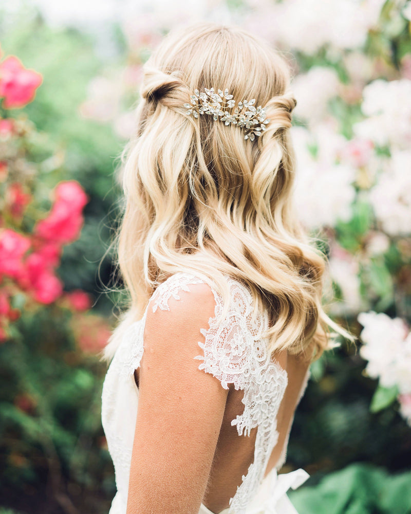 A model wears her hair styled down with soft waves and pieces on both sides pinned up. She wears the Enchanted Crystal Bridal Comb in the back.