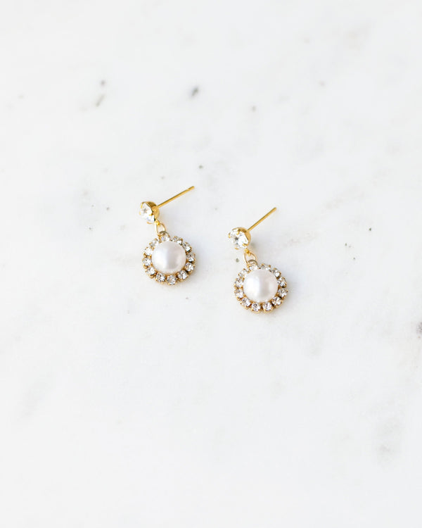 Flatlay of the Halo Pearl Drop Bridal Earrings in gold with freshwater pearl.
