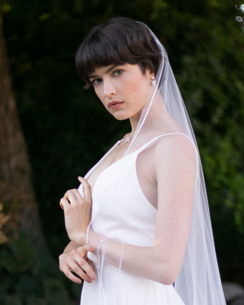 A bride wears the Primrose Ribbon Veil in light ivory.