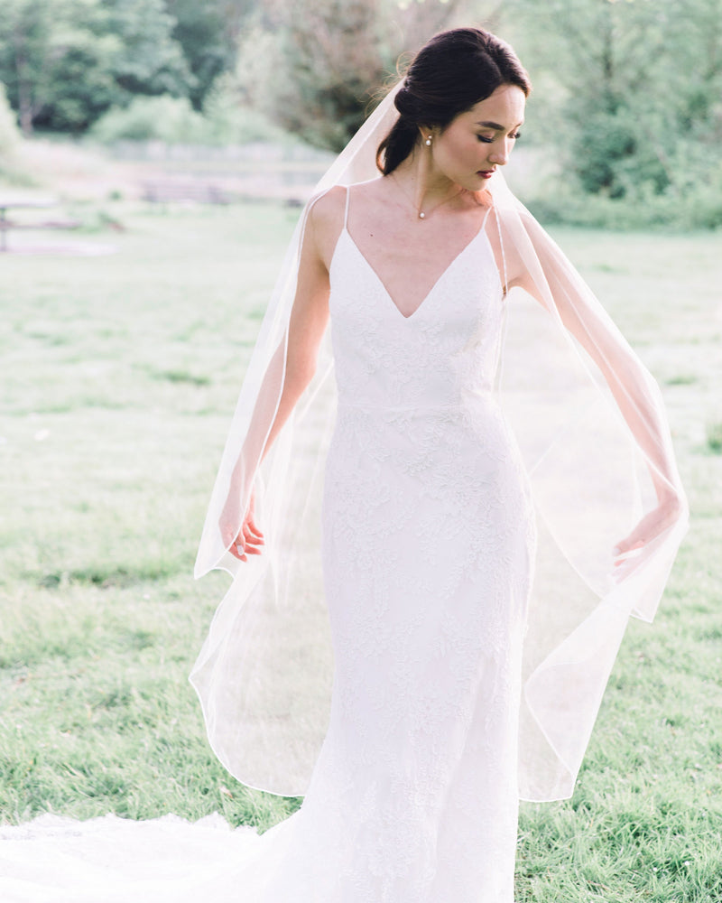 A bride wears the Primrose Veil; a ballet length veil with ribbon edge and no gathers.