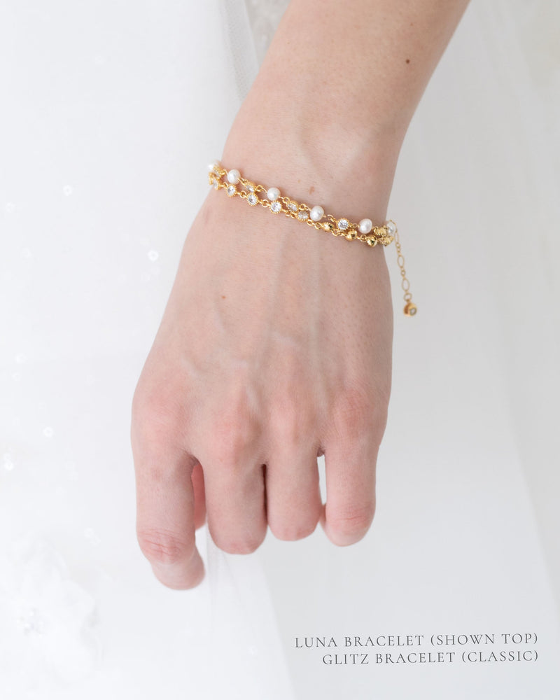 A close view of stacked bracelets, featuring the Luna Pearl and Crystal Bridal Bracelet and the Glitz Classic Bracelet in gold.