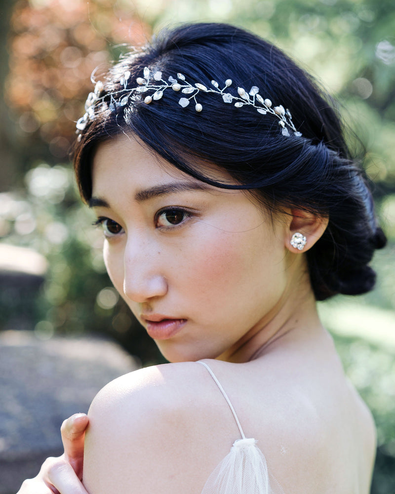 A model with her hair styled in a low updo wears the Moonflower Bridal Hair Vine in silver.