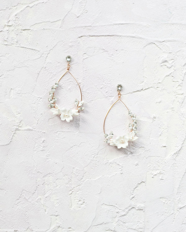 Flatlay view of the Astra Floral Statement Earrings in rose gold with ivory flowers.
