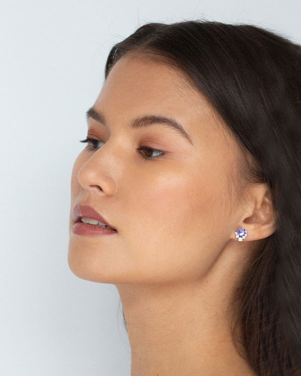 A bridesmaid wears the Celestial Crystal Cluster Earrings in rose gold/tanzanite in the petite 6mm size.