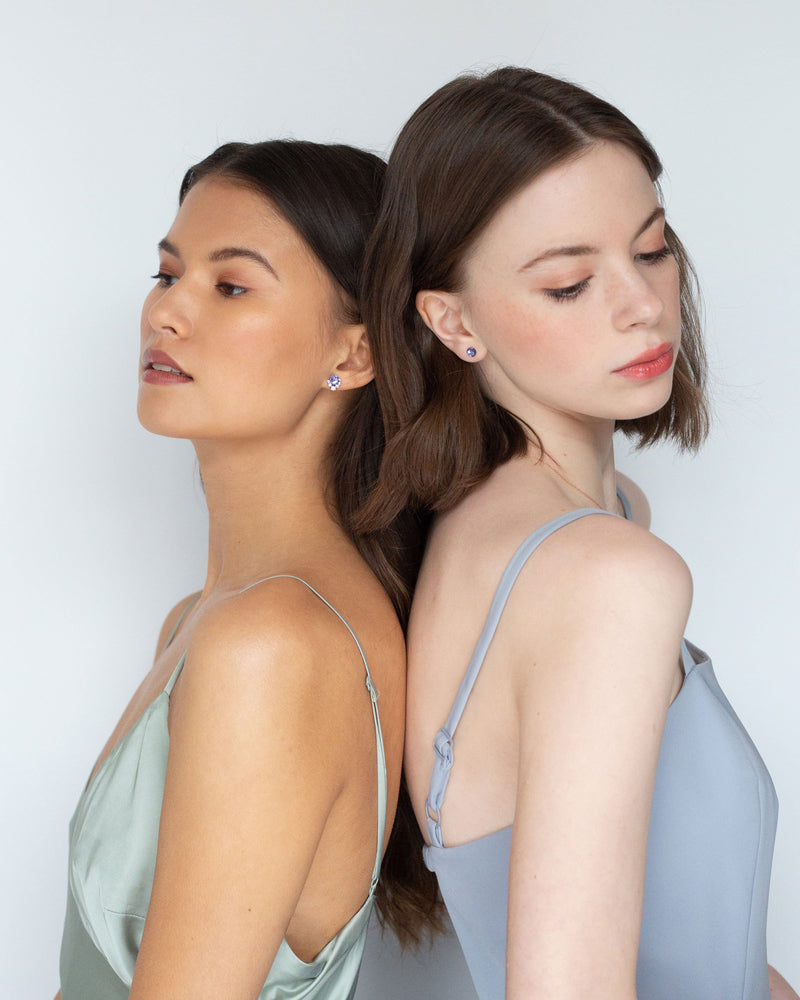 Two models wear bridesmaid jewellery. On left, she wears the Celestial Crystal Stud Earring in rose gold/tanzanite. On the right, she wears the Starry Eyed Stud Earrings in tanzanite