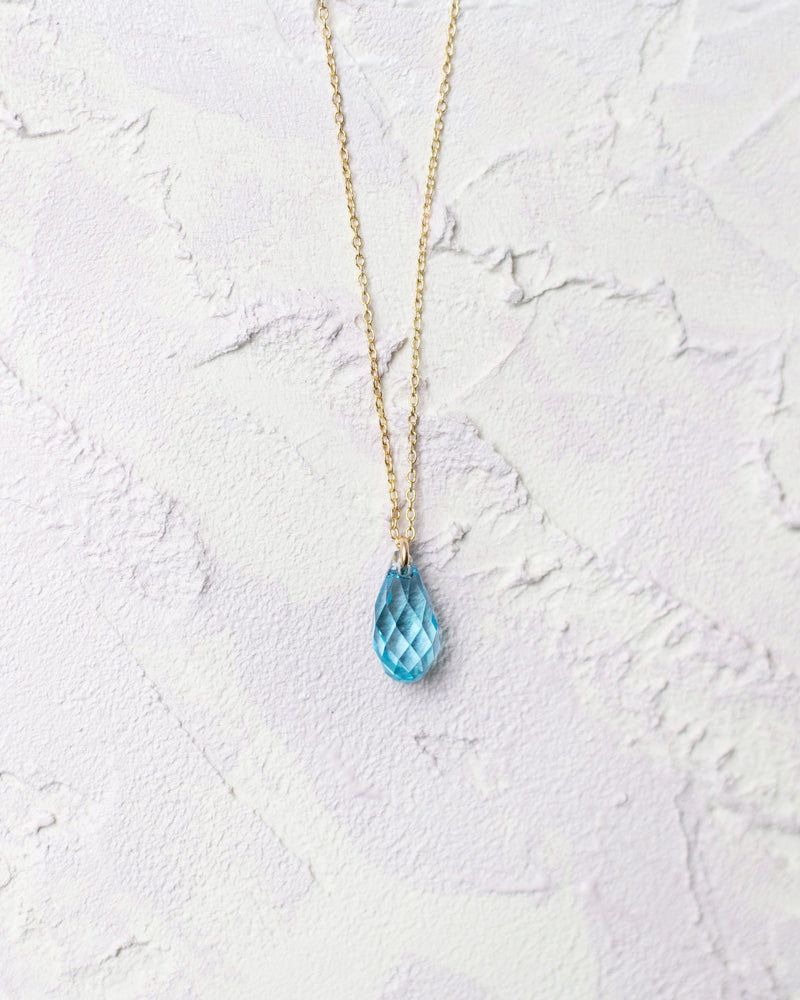 Close view of the aquamarine crystal drop on the Dewdrop Necklace in gold.