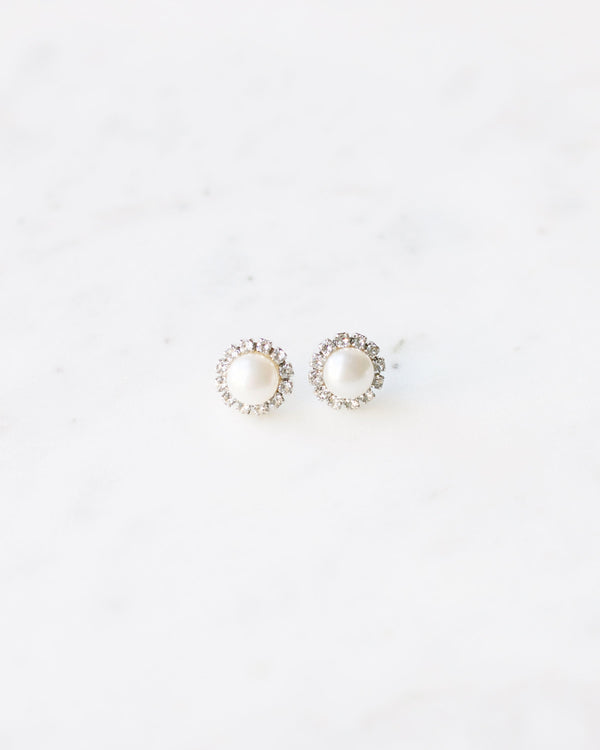 Flatlay of the Halo Pearl Stud Earrings; freshwater pearls surrounded by a halo of crystals.