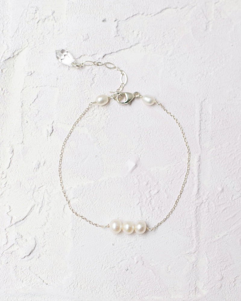 Flatlay of the Pearl Trio Bridesmaid Bracelet in silver; three freshwater pearls on a delicate chain.
