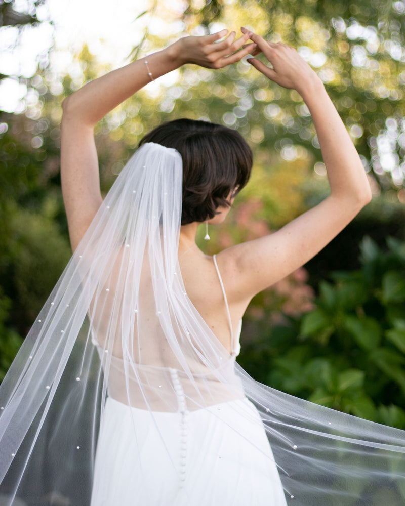 A bride wears the Akina Pearl Veil in light ivory.