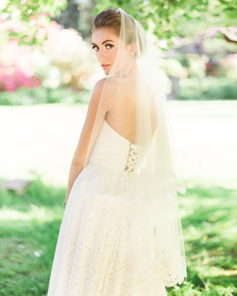 Back view of bride wearing the Amara two-layer lace fingertip bridal veil with the blusher to the back.