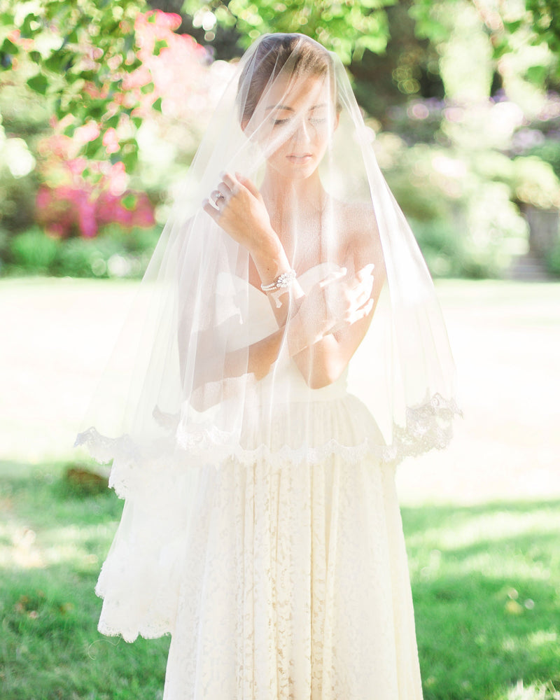 Model wearing the Amara two-layer lace fingertip bridal veil with the blusher to the front.