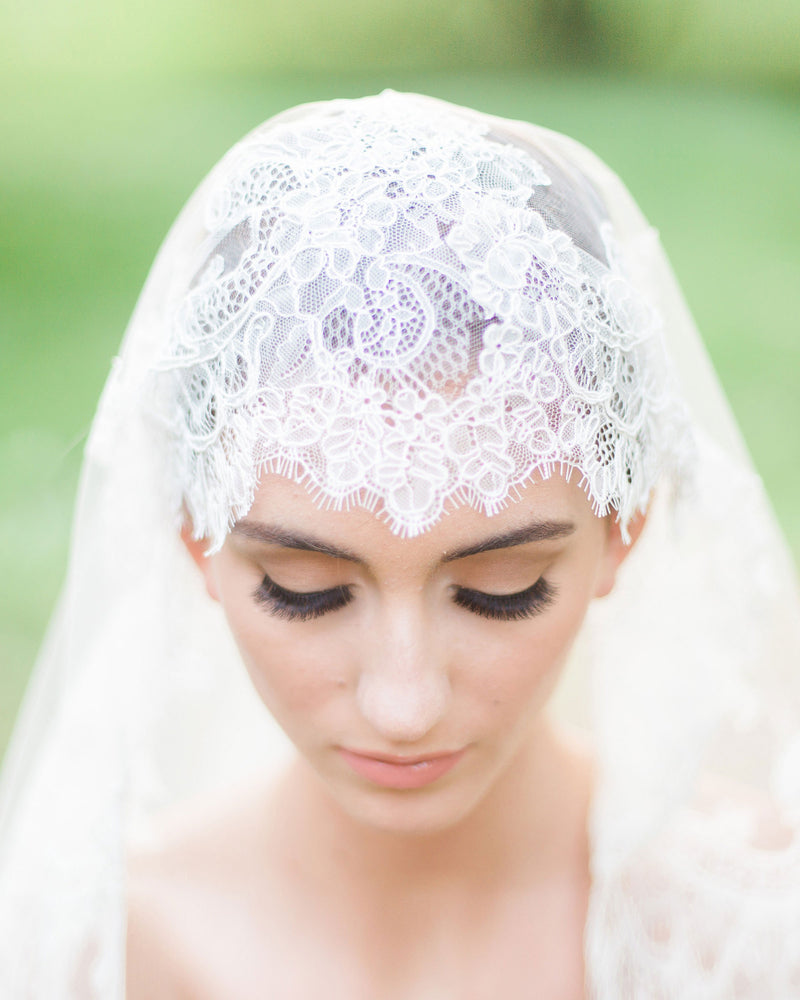 A close view of a bride wearing the Analina Mantilla Fingertip Veil.