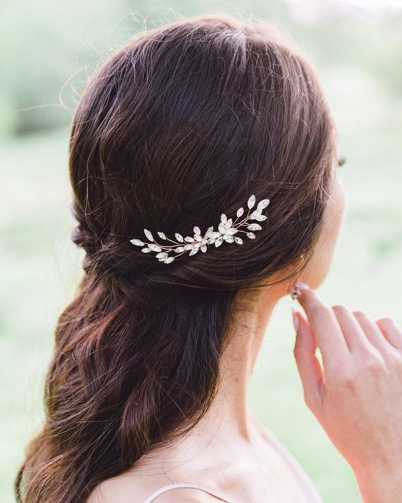 A dark-haired bride with a half-up bridal hairstyle wears the Aster Comb in rose gold and crystal.