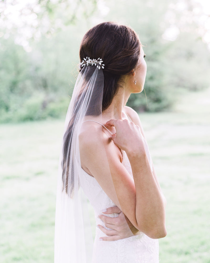Bride with a half-up hairstyle wearing a crystal bridal hair comb over the Senna Lace Veil.
