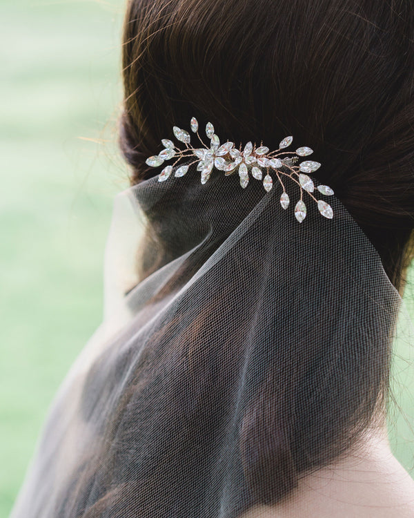 Model wearing a bridal hair comb with sparkling crystals over a veil.