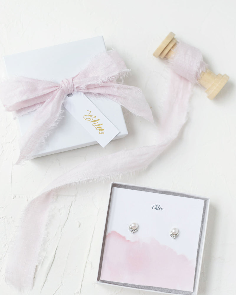 Flatlay of our Luxe Gift Wrapping with a blush linen bow, blush watercolor jewelry insert, and custom message.