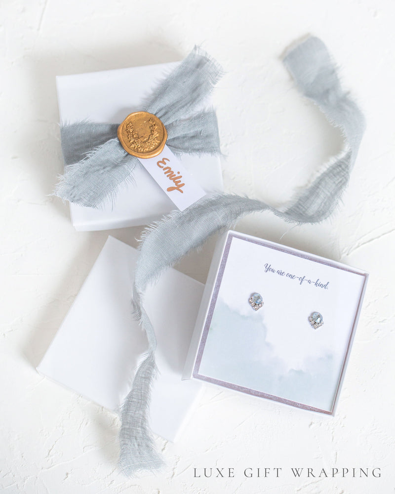 Flatlay of our Luxe Gift Wrapping with silver linen ribbon, a gold seal, and custom message.