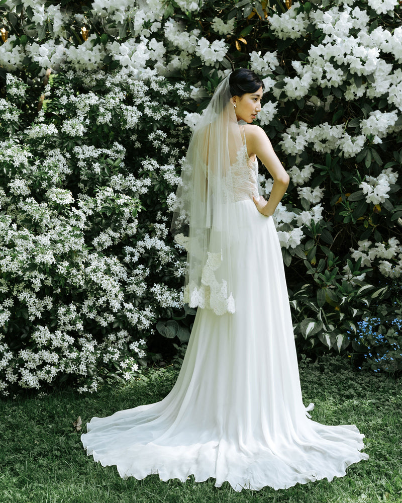 A bride wears the Azalea two-layer veil with lace border on bottom layer and soft blusher worn to the back.