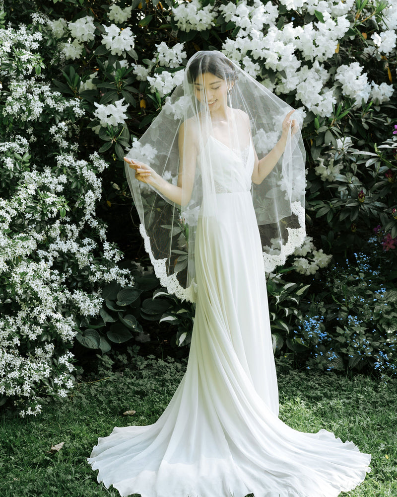 A bride wears the Azalea two-layer veil with a lace border on the bottom layer and soft blusher worn to the front.