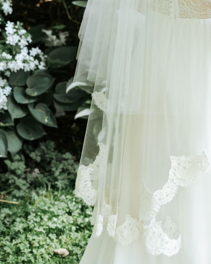 Close on model details of the Azalea veil's lace edge with scallop detail that varies from 1" to 3".