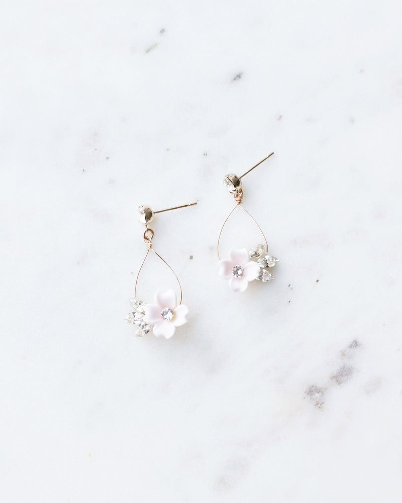 Flatlay of the all-crystal version of the Belle Fleur Earrings. hand-crafted statement earrings with delicate wire teardrop. small blush flowers and crystals hanging from a crystal stud.