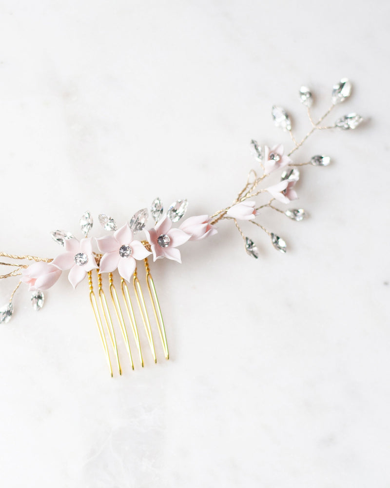 Close flatlay of the Belle Fleur Grand Comb in gold, highlighting the delicate blush flowers and crystals.