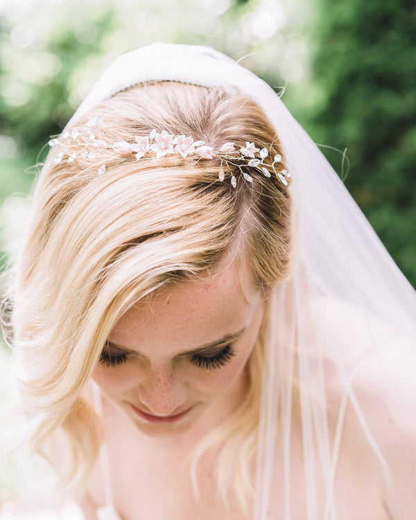 A bride with blonde hair and loose waves looks down to show the Belle Fleur Grand Comb styled as a crown on the top of her head.