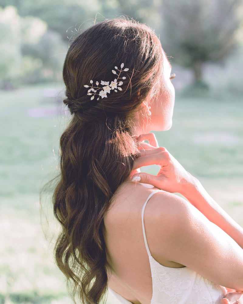 A dark-haired bride wears the Belle Fleur Hair pins in her half-up hairstyle; the pins are rose gold with blush flowers, crystals, and freshwater pearls.