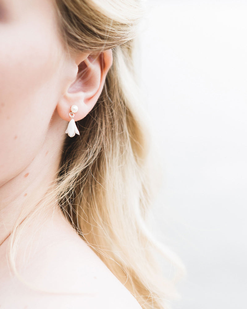 Close-up on model of the Belle Fleur Petite Earrings, which feature a delicate flower hanging from a pearl stud.