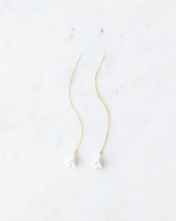 Flatlay of delicate ear threader earrings in gold with tiny blush polymer clay flower drops.