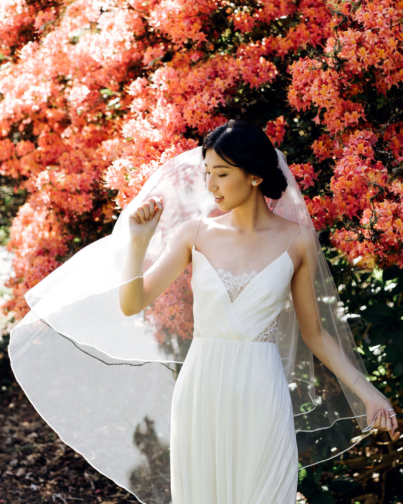 Model wearing calla wedding veil with ribbon edging