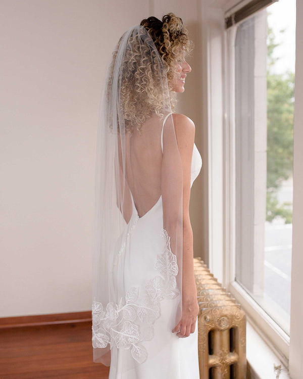 A model wears the Camellia Beaded Lace veil in fingertip length.