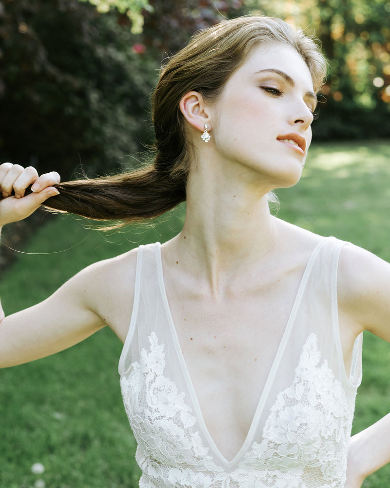 A bride with a low pony is wearing the Celestial Crystal Drop Earrings in silver, all crystal.