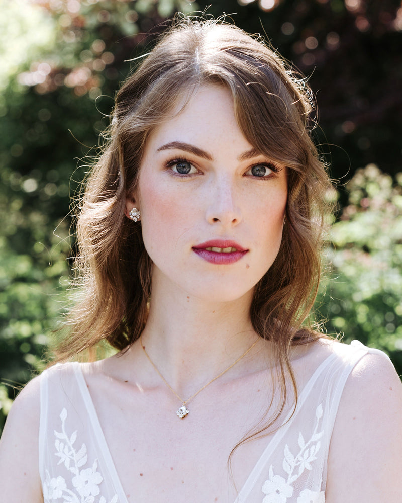 A bride with auburn hair models the Celestial Crystal Drop Necklace in gold/crystal and matching Celestial Crystal Stud Earrings.
