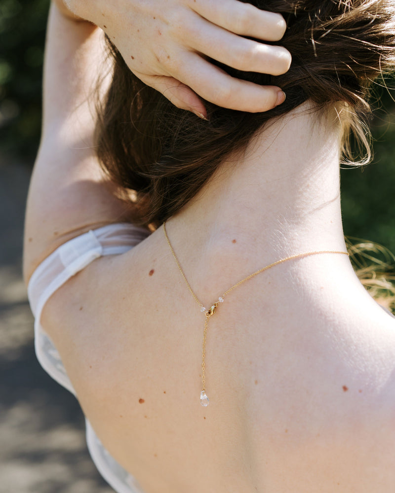 A back view of a bride wearing our Celestial Crystal Drop Necklace, showing the dainty crystal drop at the back.