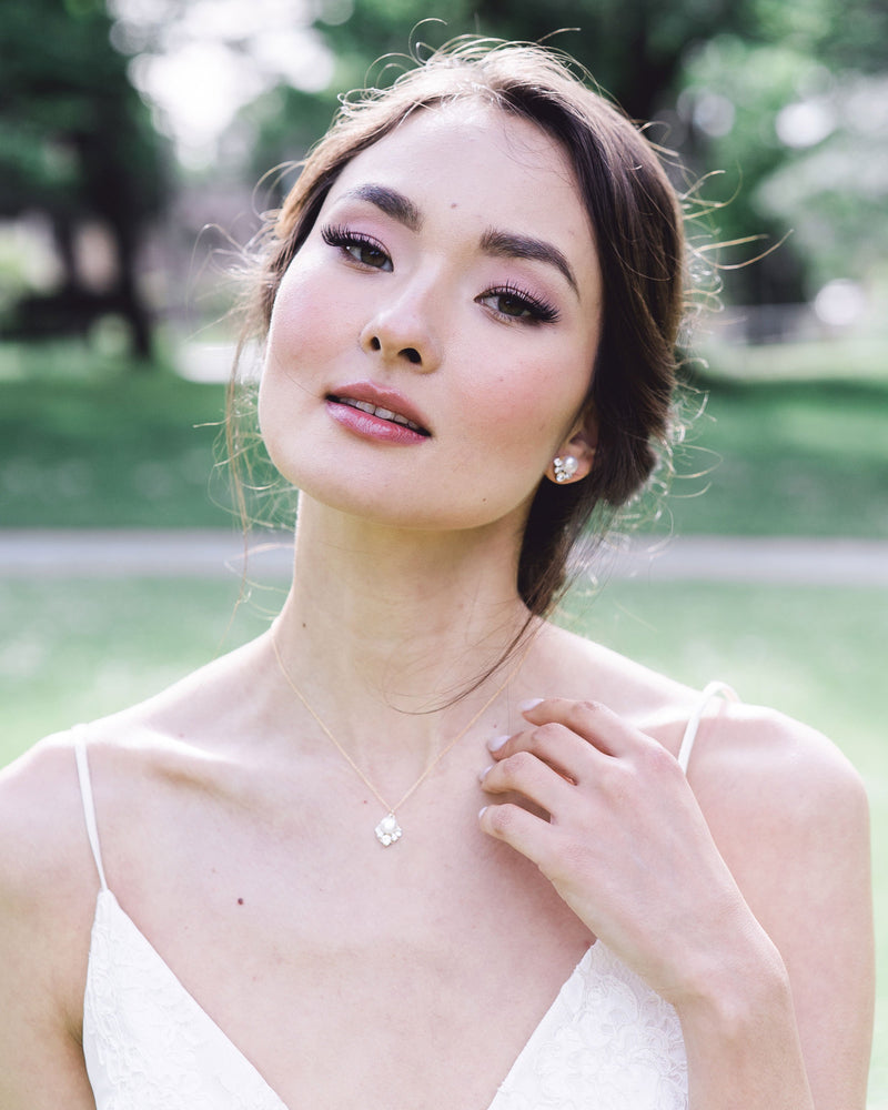 A bride wears the Celestial Pearl Jewellery Set with a drop pearl necklace and matching pearl stud earrings in gold with freshwater pearls.