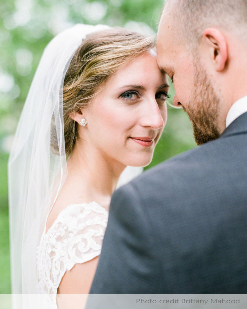 A bride wearing the Celestial Pearl Cluster Earrings in silver with cream and the Leila Ribbon Veil.