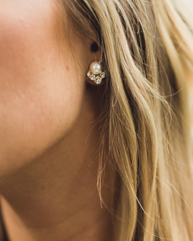 A close-up on a model wearing the Celestial Pearl Cluster Earrings in gold with cream faux pearls. 